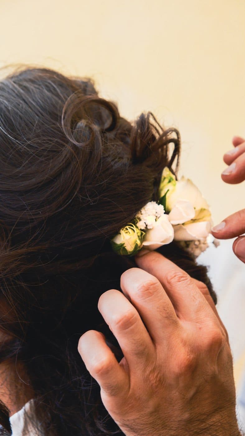 Blumen werden ins Haar der Braut gesteckt