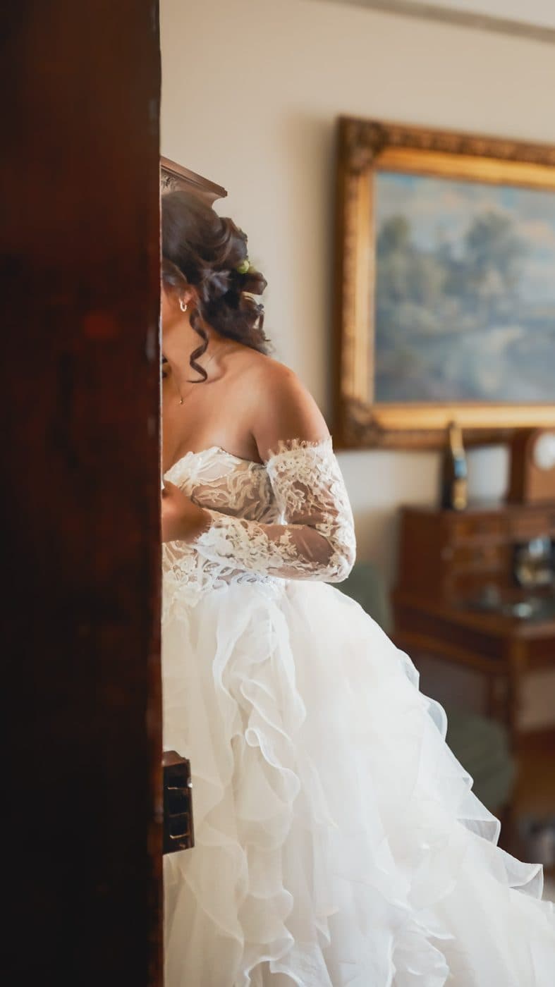Braut im Brautkleid, halb verborgen hinter der Tür